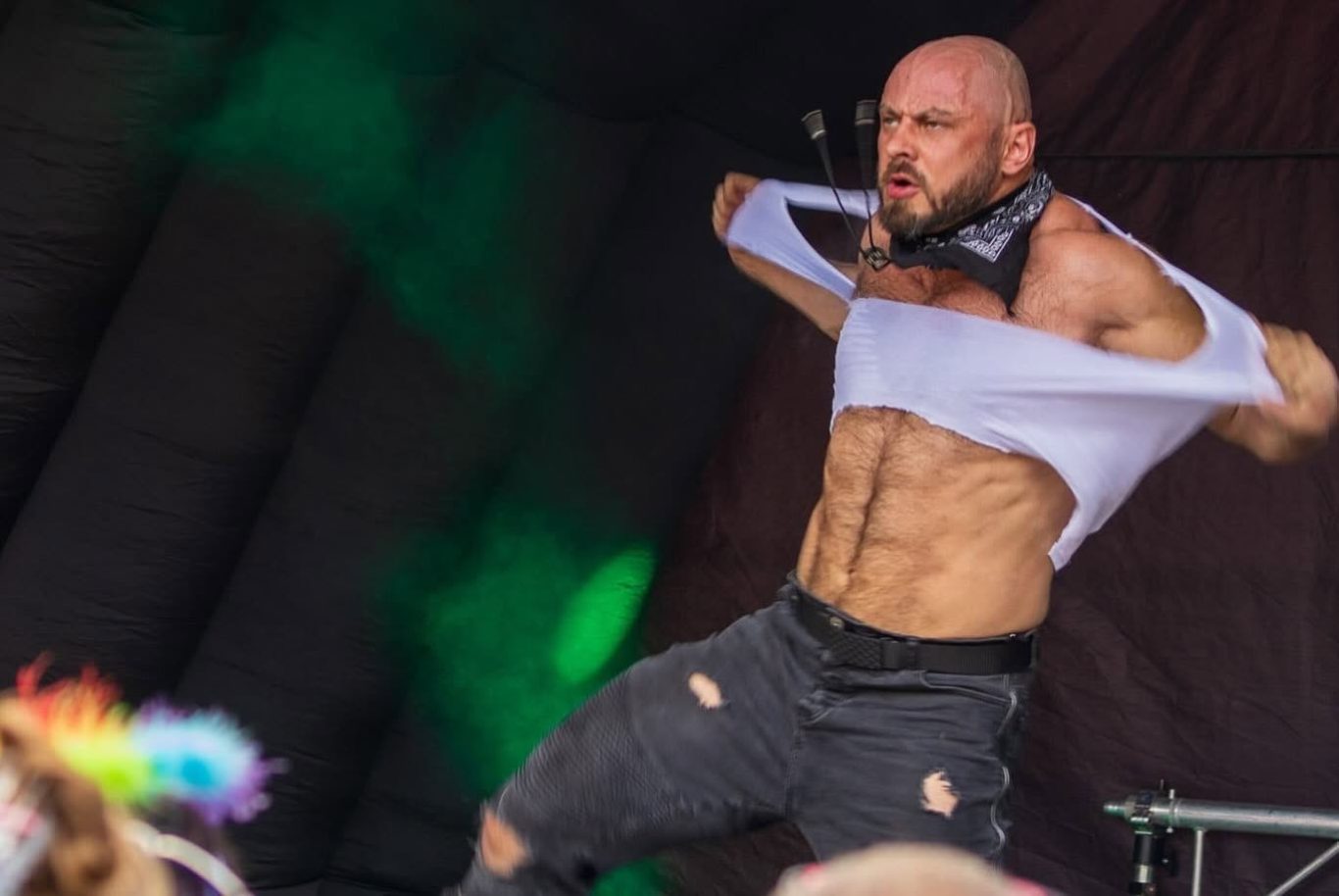 Marshall Arkley - 2024 Muscular performer removing his shirt on stage during a lively event.