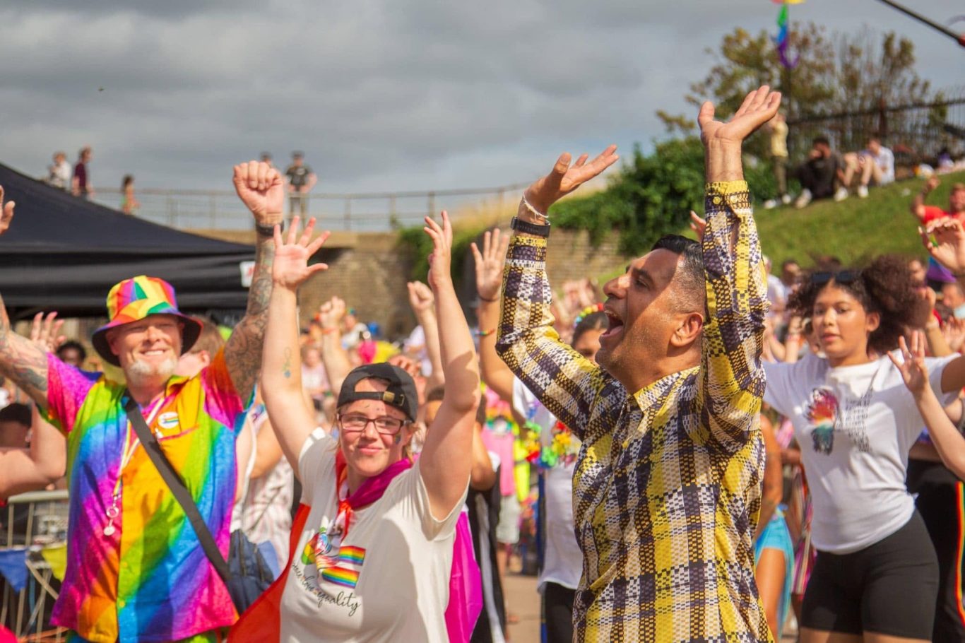 Crowd celebrating with hands raised at a vibrant Pride event.