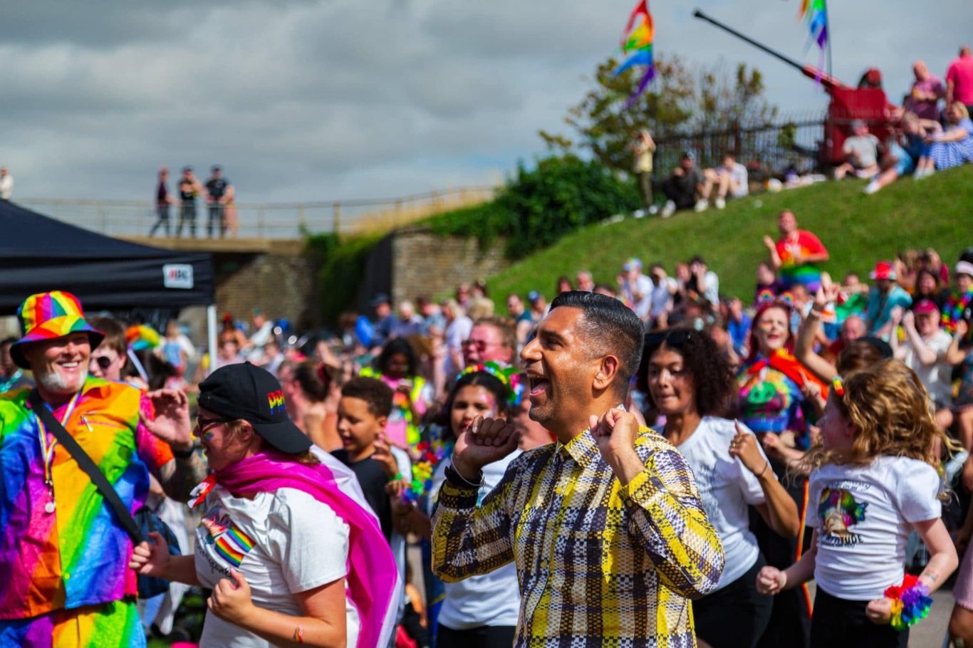 A joyful crowd at a Pride event, celebrating with vibrant outfits and flags.