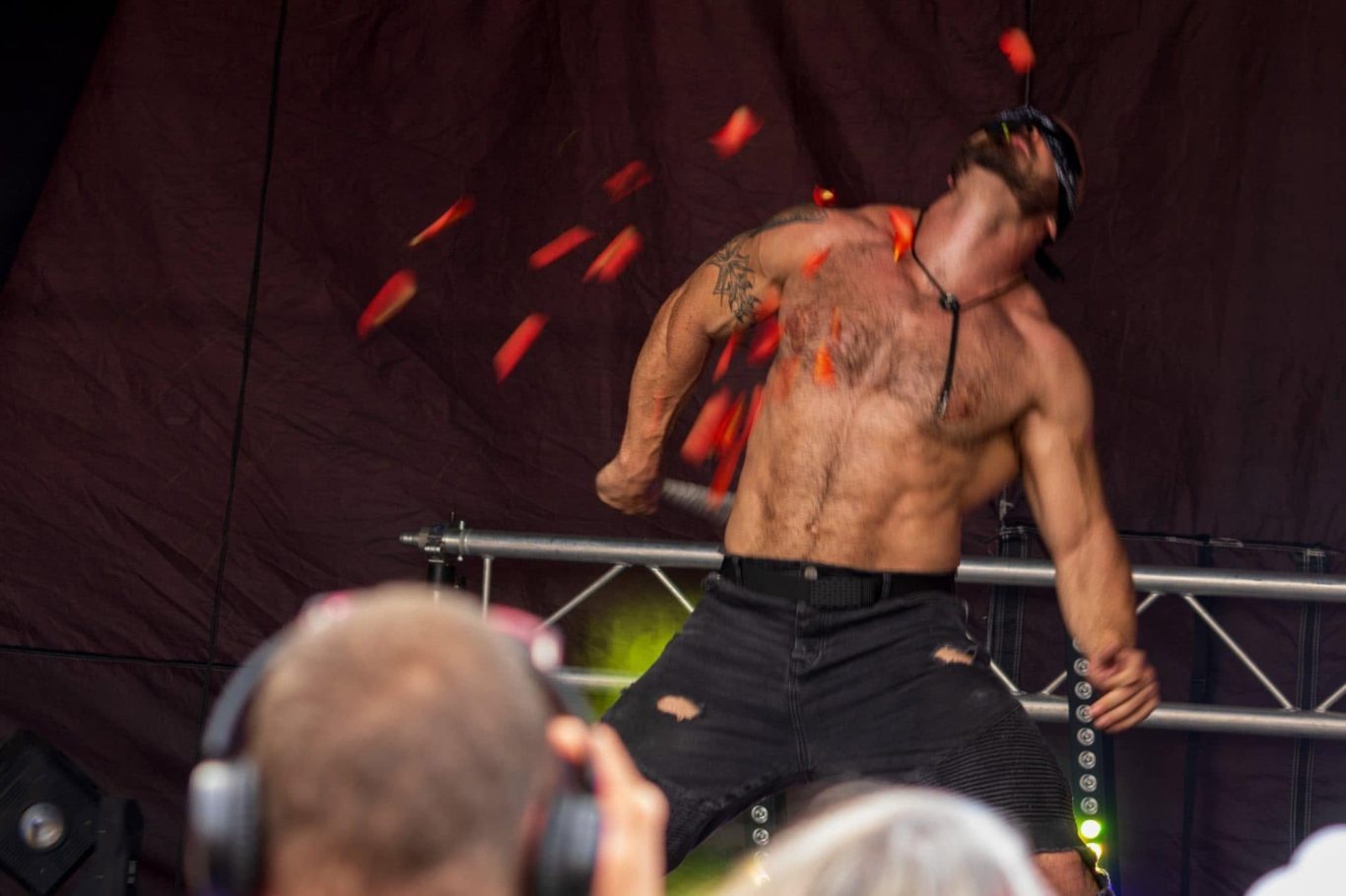 Marshall Arkley - 2024 A muscular performer throwing objects during a live outdoor show.