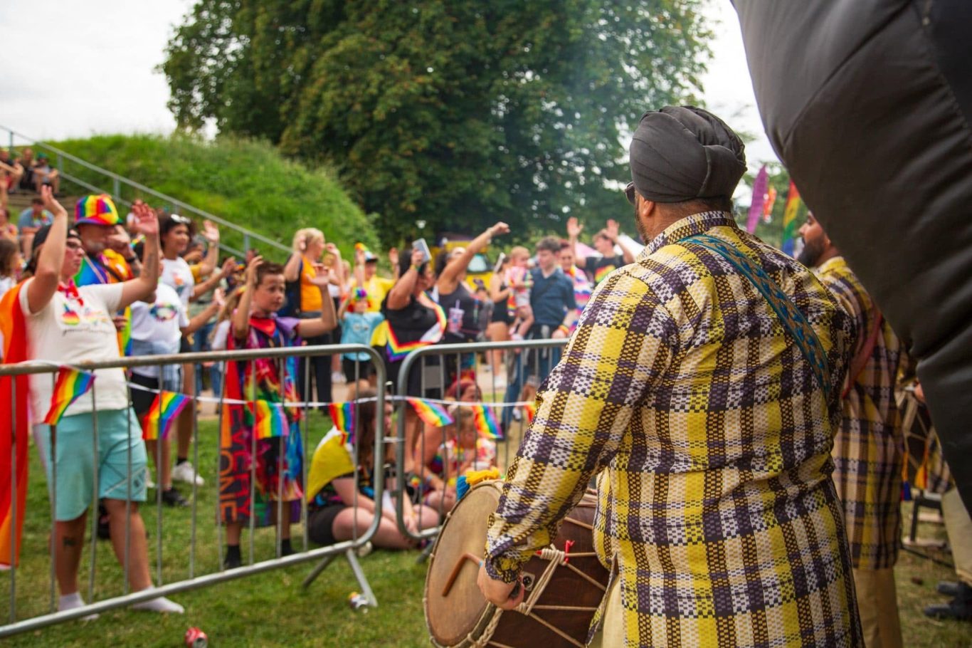 Kings of Dohl Crowd celebrating at a pride event, with a performer playing a drum.