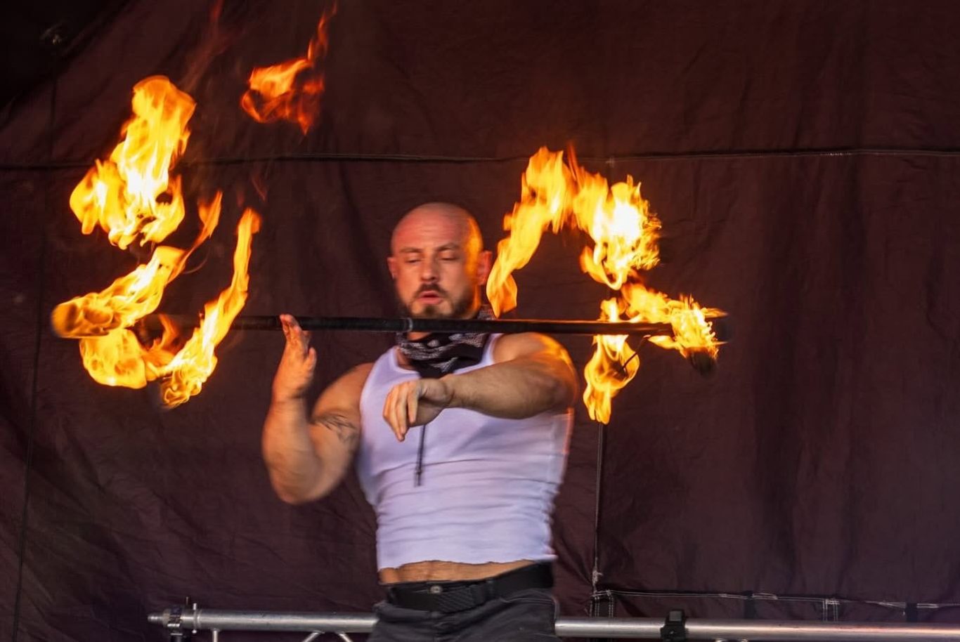 Marshall Arkley - 2024 A performer juggling flaming torches on stage.