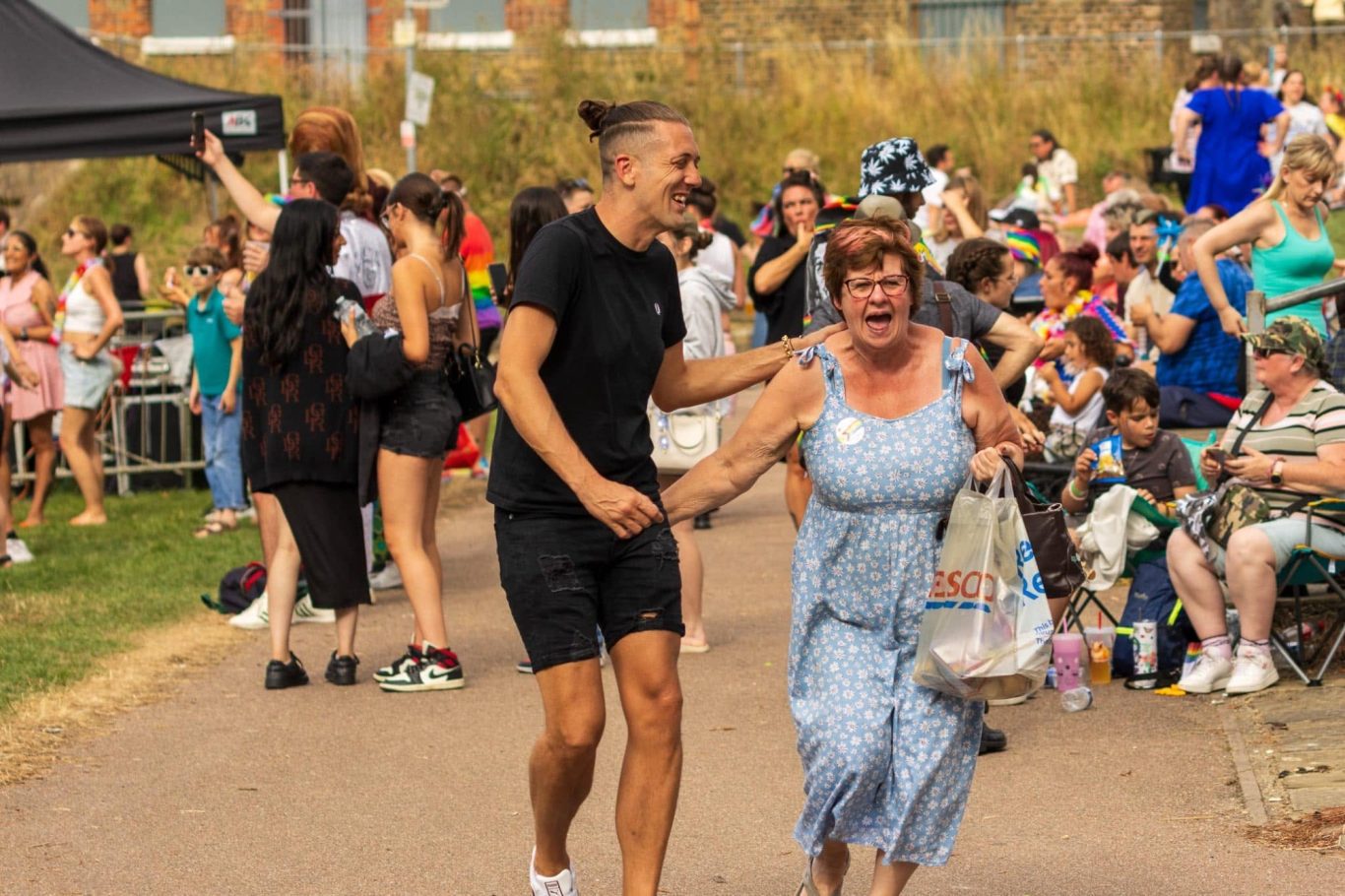 People joyfully dancing in a lively outdoor event, surrounded by an enthusiastic crowd.
