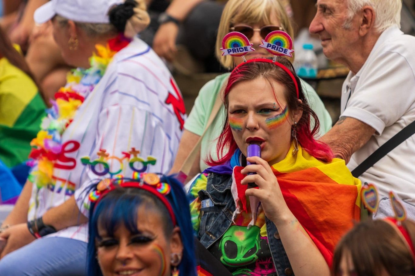 A group of people at a celebration, wearing colourful outfits and accessories.