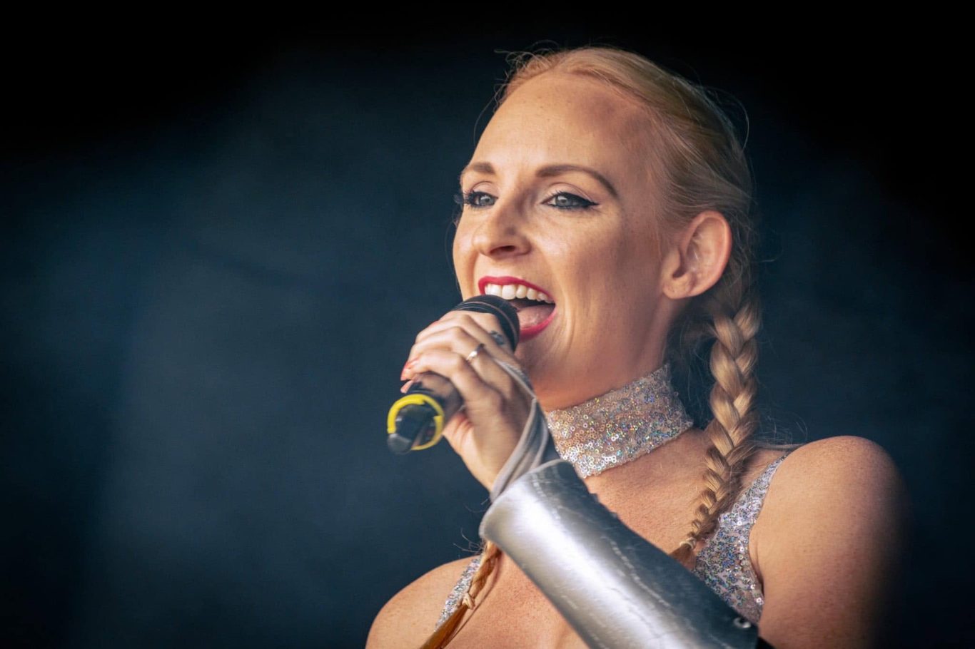 Kylie On Show - 2024 Female singer with braided hair performs passionately, microphone in hand.