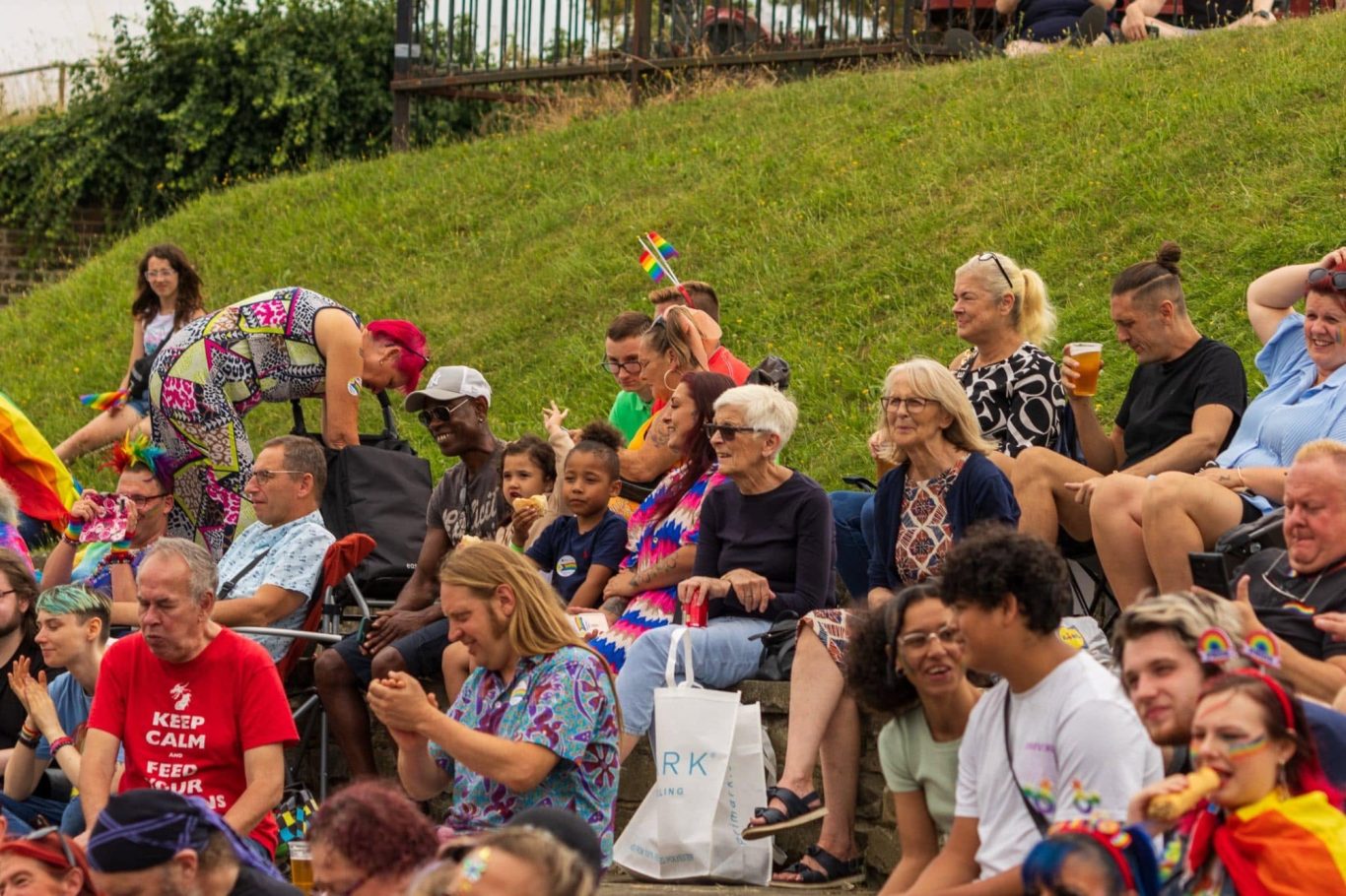 A diverse crowd of people seated outdoors, enjoying a festive event.