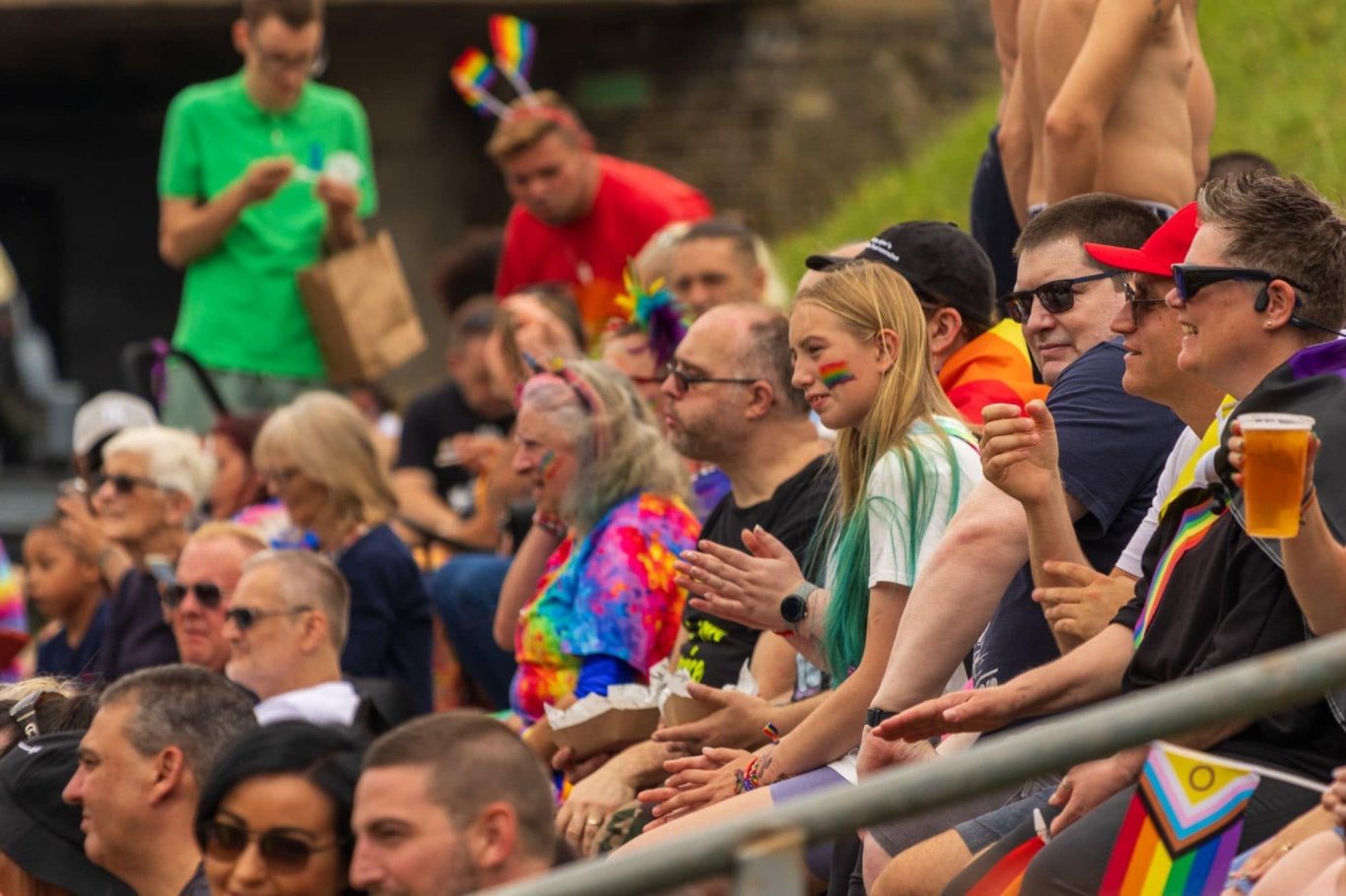 A diverse crowd at a celebration, wearing colourful outfits and enjoying the event.