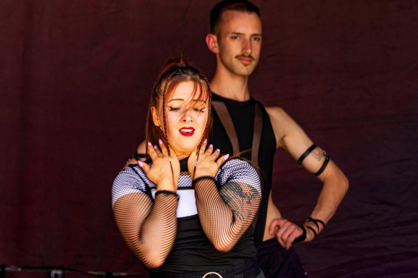Haus of Heels - 2024 Two performers in striking costumes pose on stage, showcasing expressive body language.