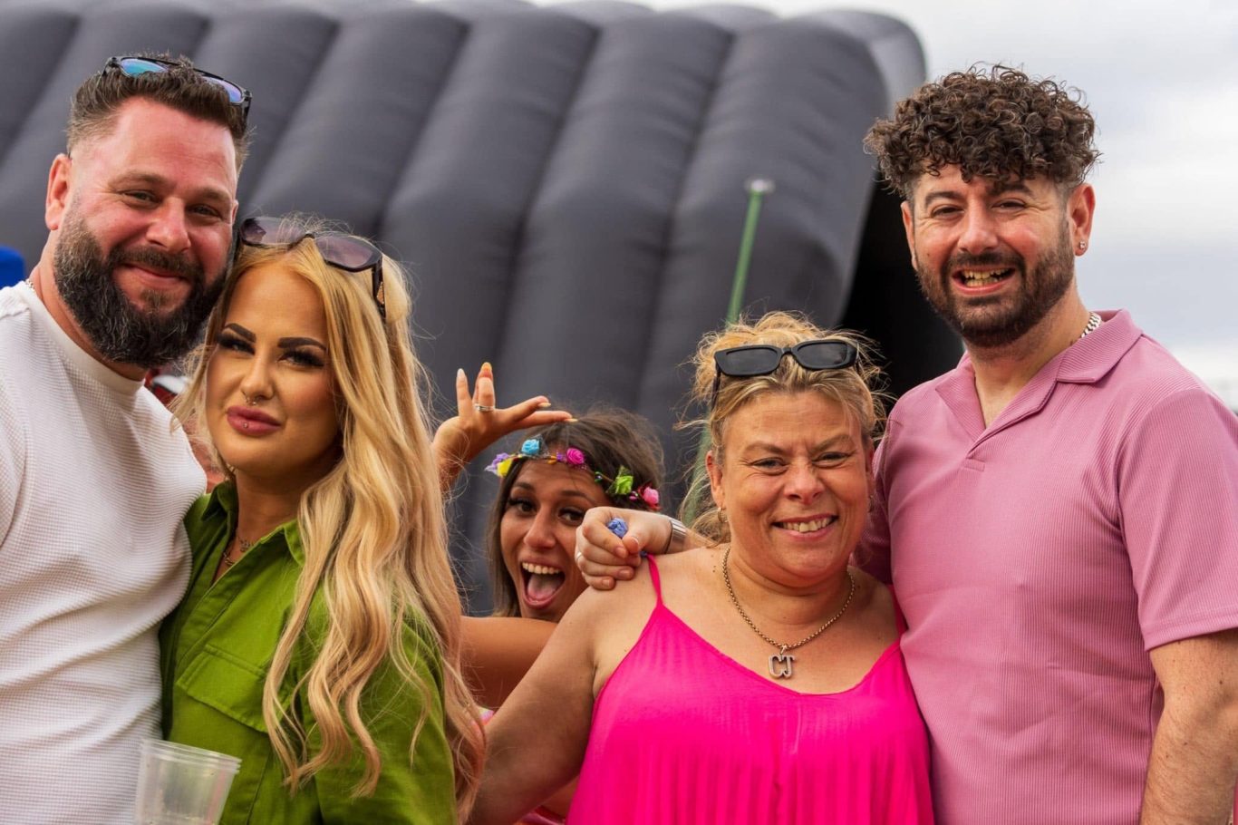 A group of four people smiling, with an inflatable structure in the background.