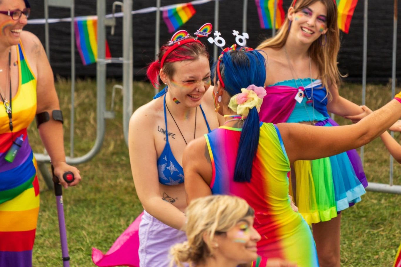 A group of people celebrating at a vibrant Pride event, wearing colourful outfits.