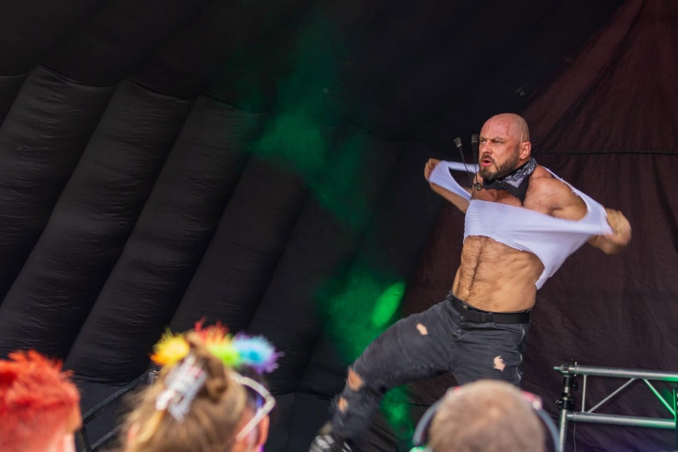 Marshall Arkley - 2024 A performer theatrically removes their shirt on stage, engaging with the audience.