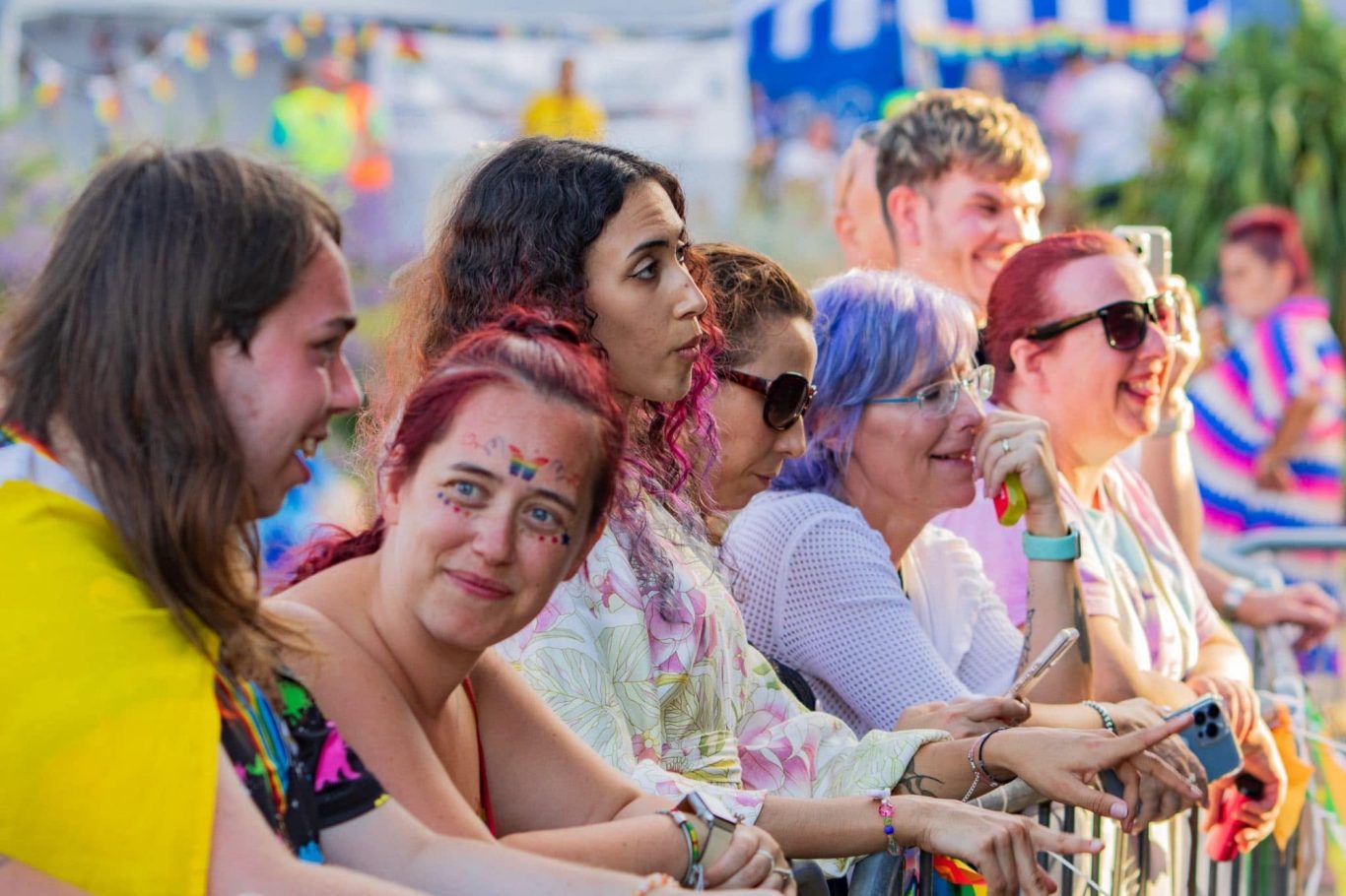 A diverse group of people enjoying a festive event, with colourful attire and joyful expressions.