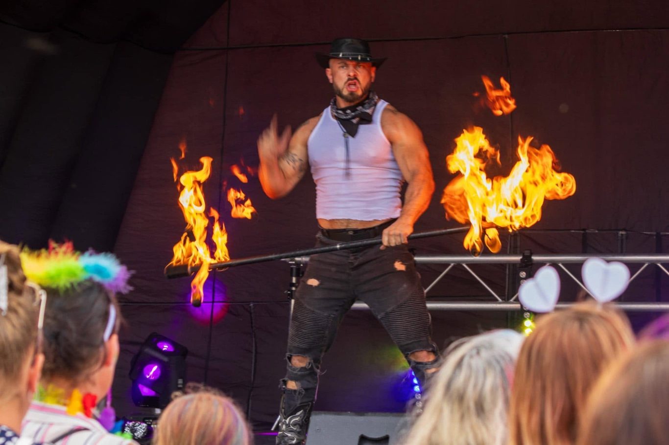 Marshall Arkley - 2024 Fire performer in a sleeveless top captivates an audience with flaming poi.