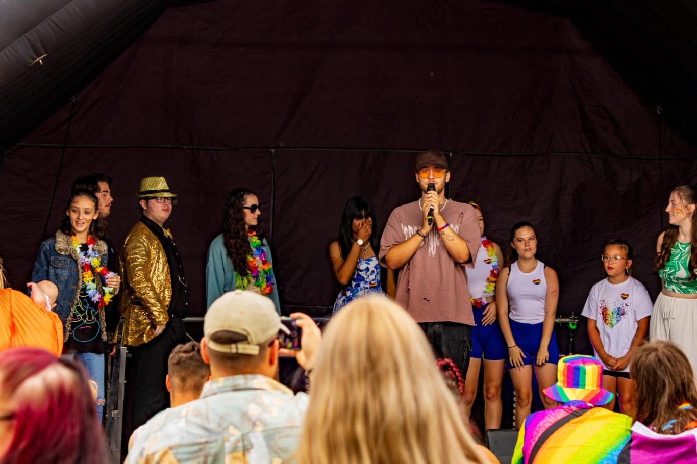 GYG - 2024 A diverse group of people on stage at a colourful event, addressing the audience.