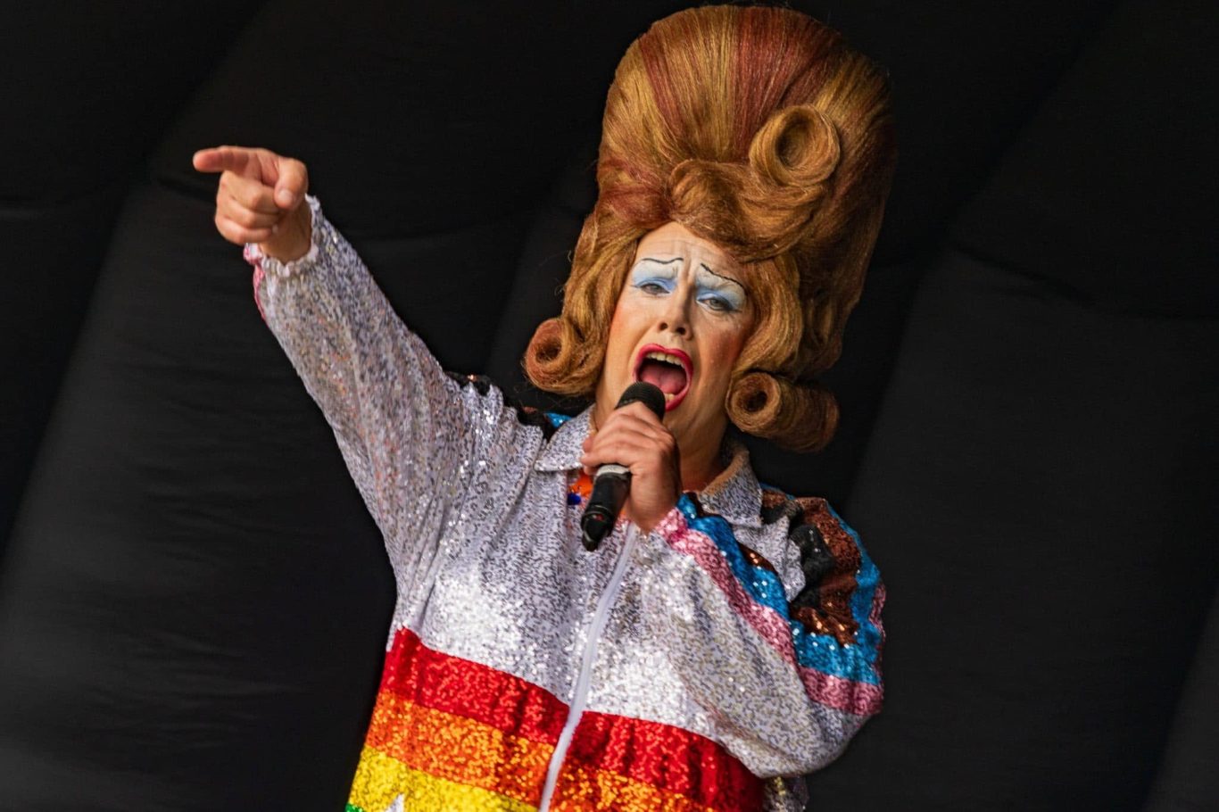 Mama G - 2024 A drag performer in a glittery outfit passionately gestures while singing.