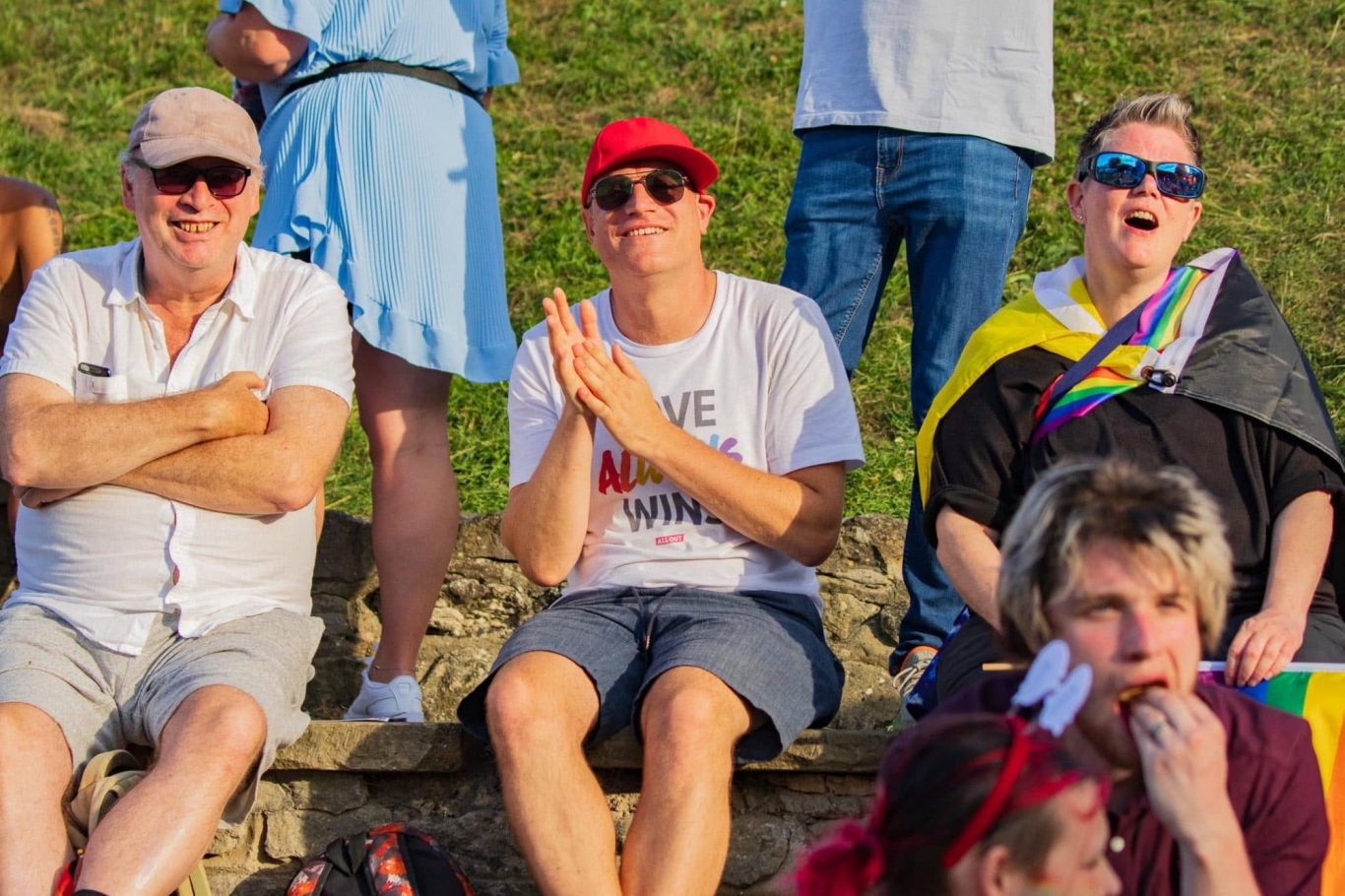 A diverse group of people sitting together, enjoying an outdoor event with vibrant attire.