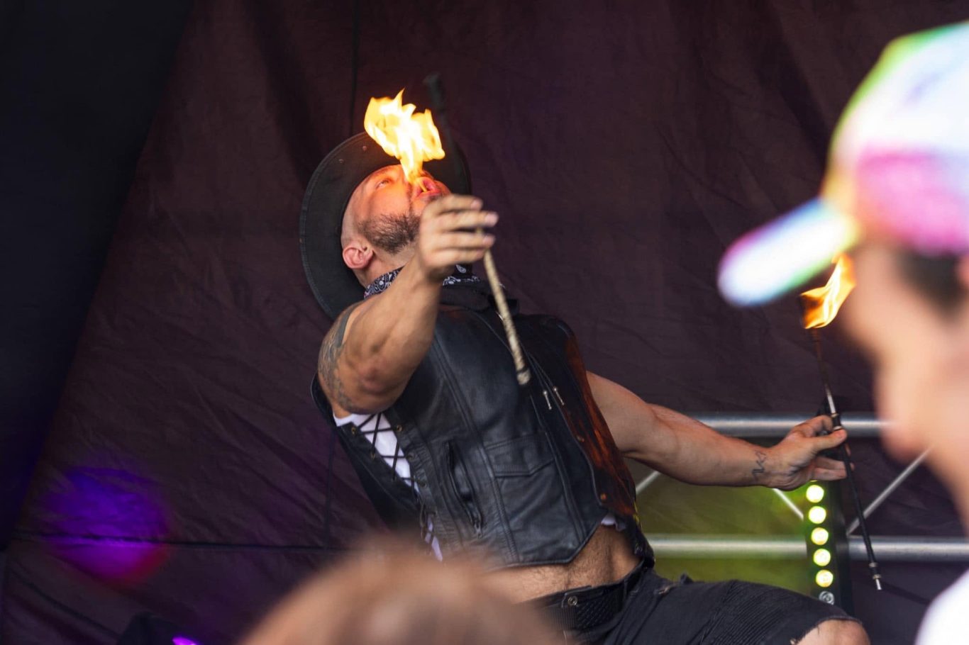 Marshall Arkley - 2024 Performer engaging in fire juggling, wearing a black vest and cowboy hat.