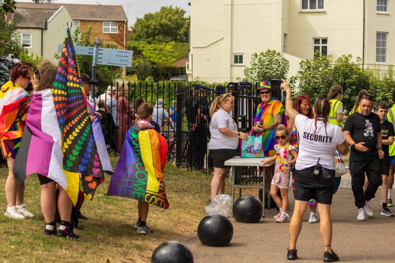 A vibrant outdoor event with people in colourful outfits and flags celebrating together.