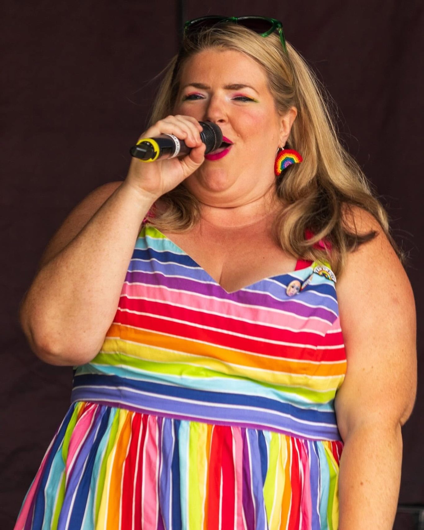GYG - 2024 Woman singing into a microphone while wearing a multicoloured striped dress.