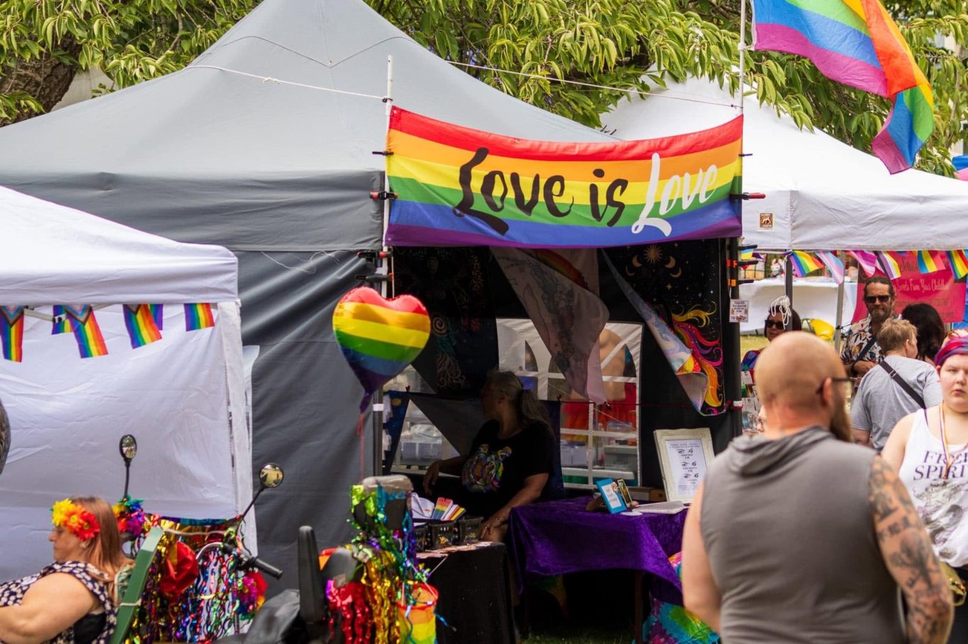 Colourful tents adorned with rainbow flags at a vibrant pride event.