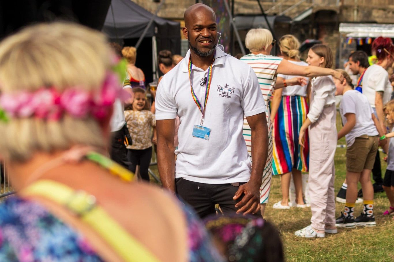 A man in a white shirt stands among a lively crowd at an outdoor event.