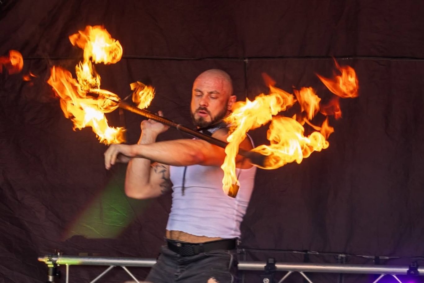 Marshall Arkley - 2024 Fire performer manipulating flaming torches with skillful movements.