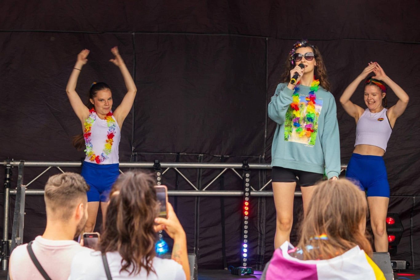 GYG - 2024 Three performers on stage, two dancing and one singing, in colourful outfits.