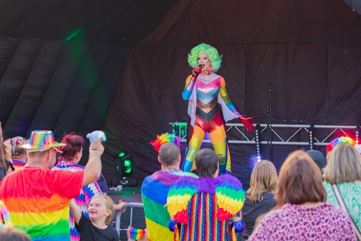 Divina DiCampo - 2024 A performer in a colourful outfit sings on stage to an enthusiastic crowd.