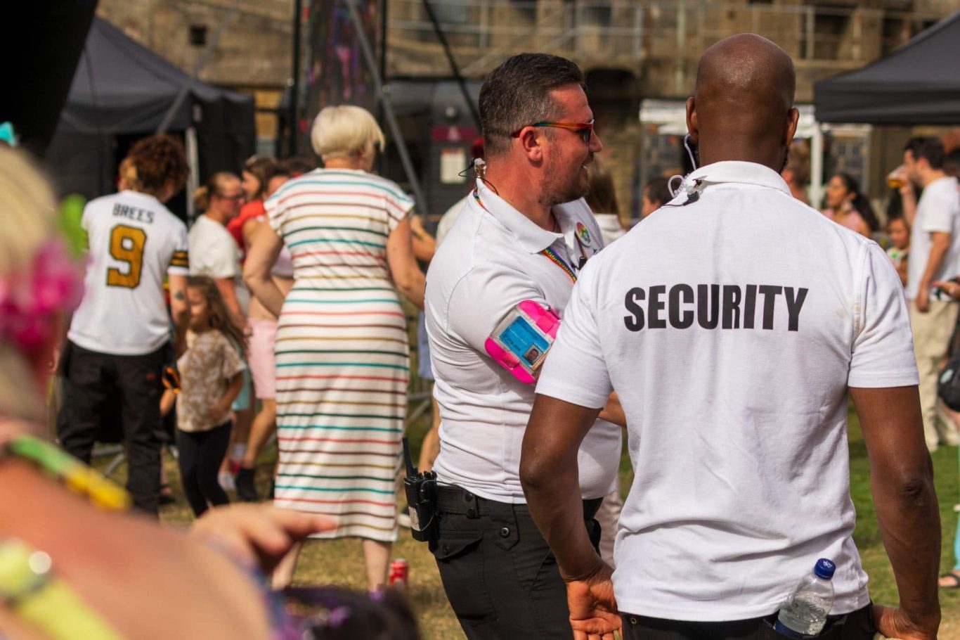 A busy outdoor event with security staff and attendees enjoying the festivities.