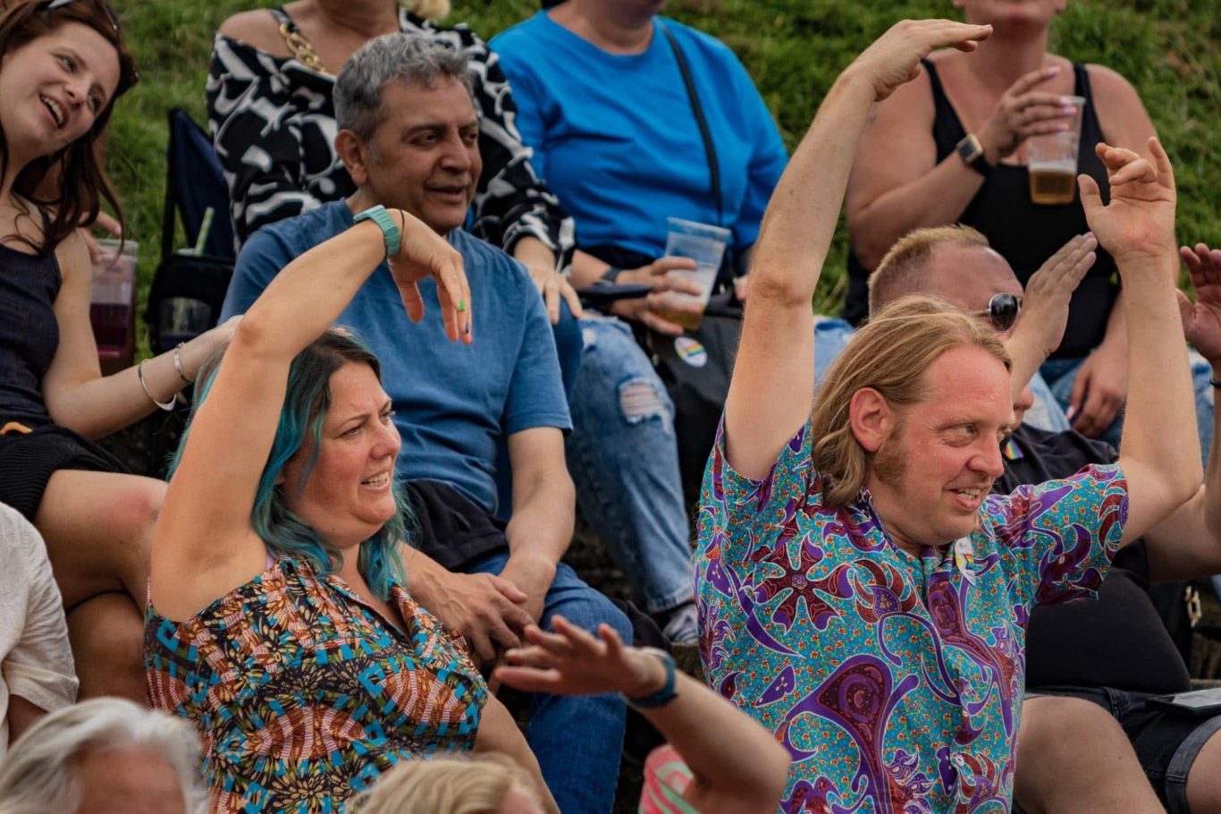 A lively audience enjoying a performance, with two people dancing and smiling.