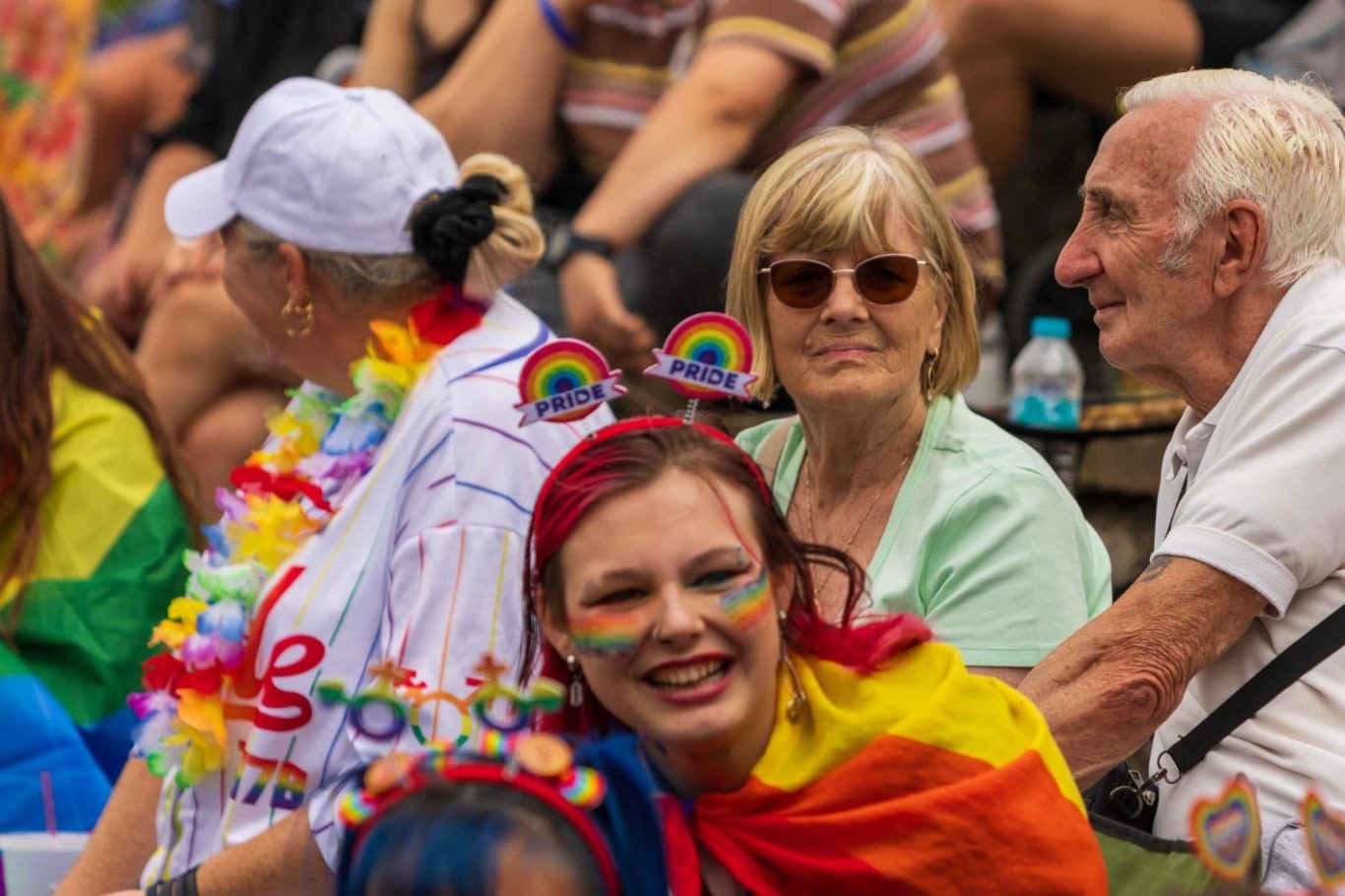 A diverse group of people celebrating with rainbow colours at a festive event.