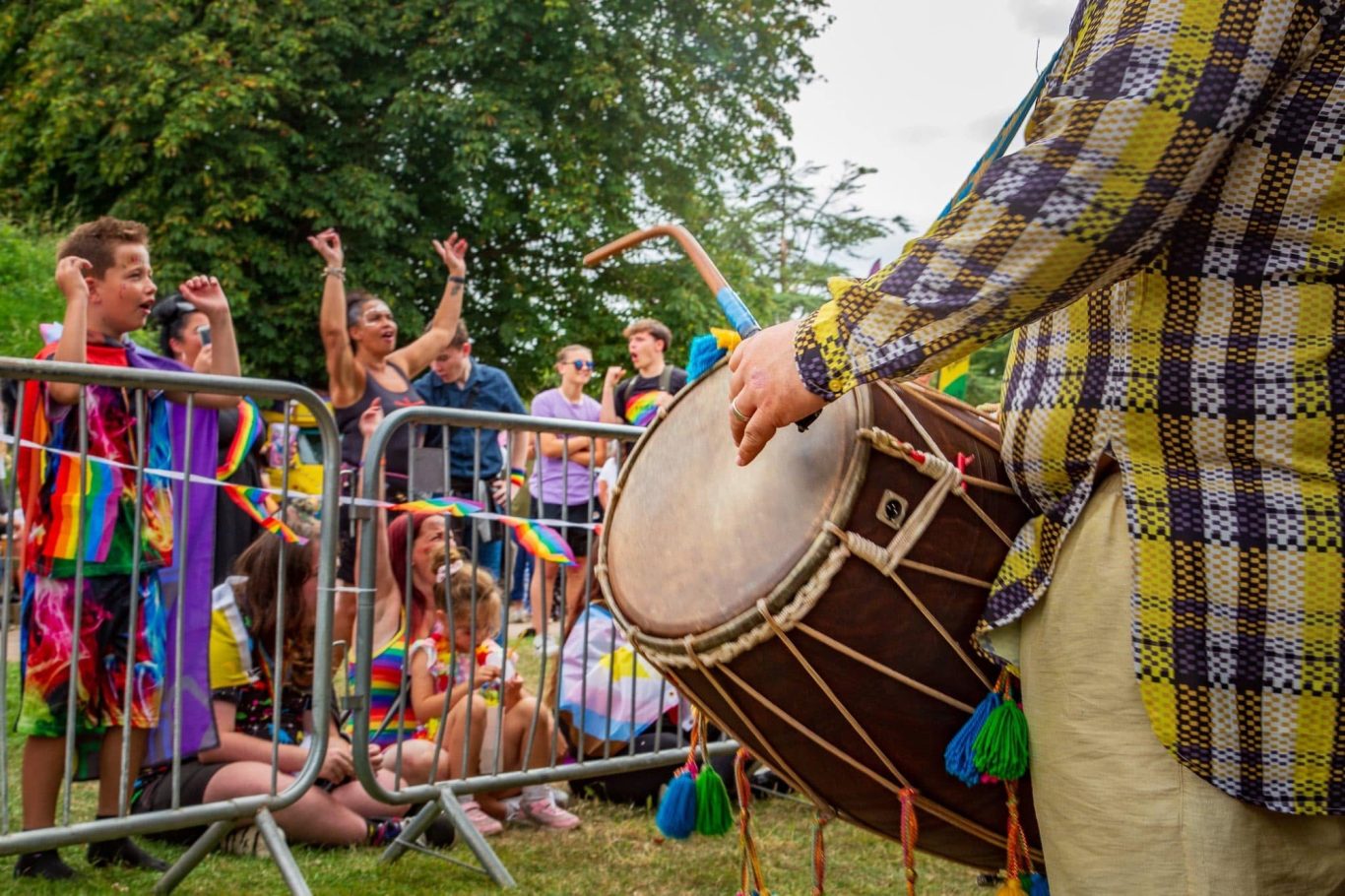 Person playing a drum in front of a lively crowd at a festive outdoor event.