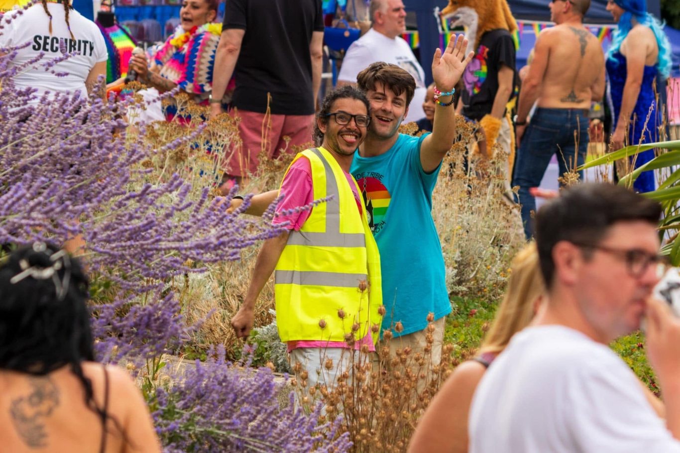 Two people in bright clothing smiling and posing at a vibrant outdoor festival.