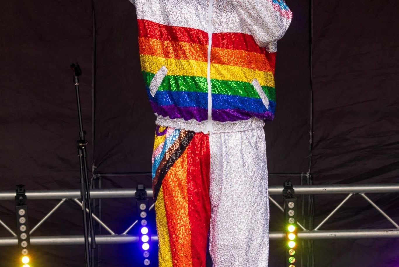 Mama G - 2024 Performer wearing a rainbow-striped tracksuit singing on stage.