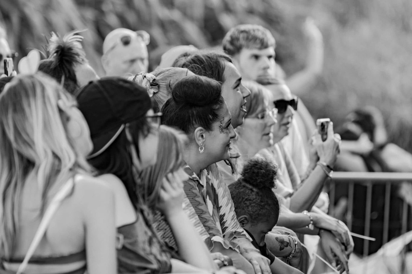 A group of people enjoying a sunny outdoor event, some smiling and interacting.