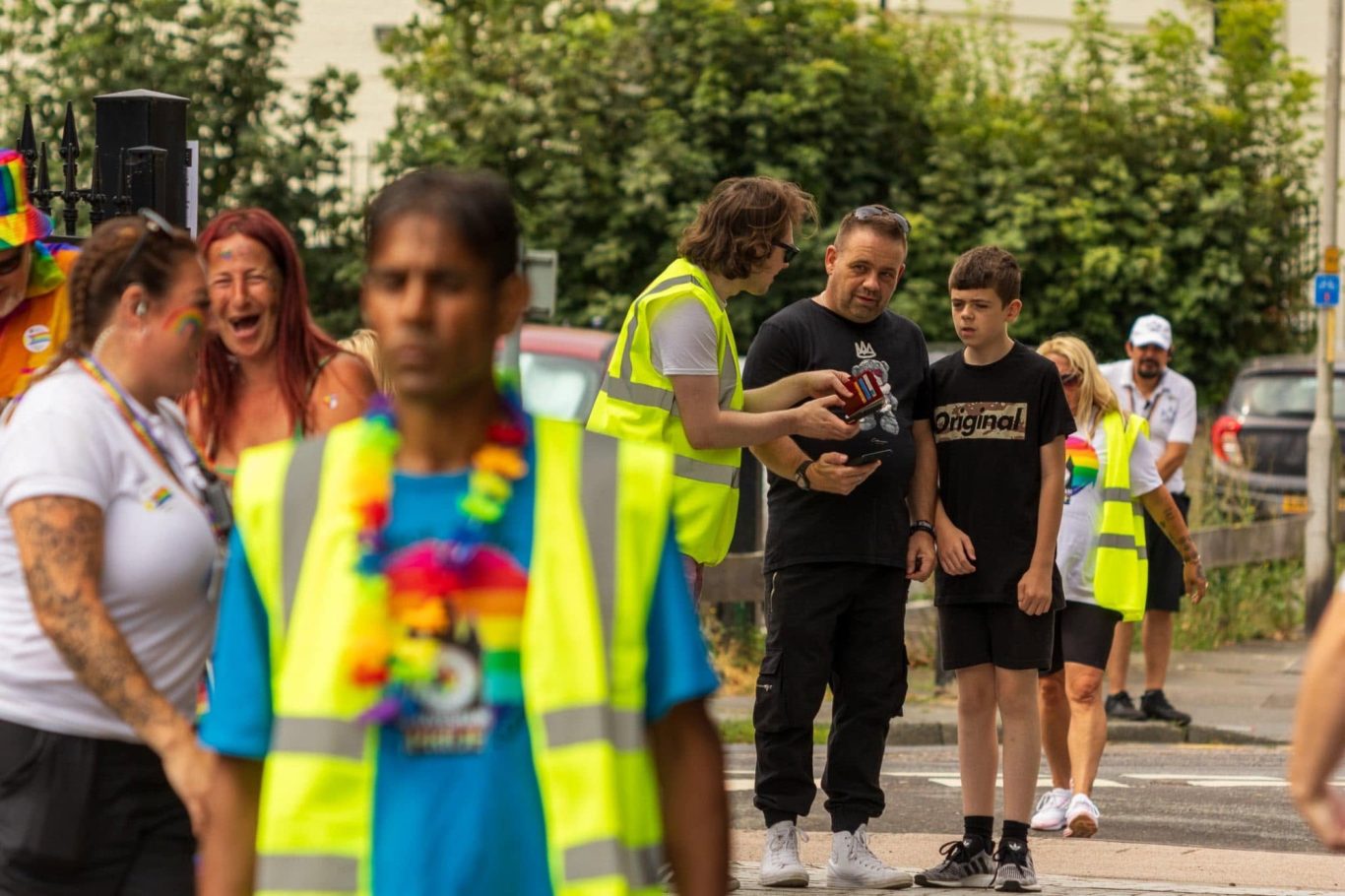 A group of people celebrating at an outdoor event, wearing bright clothing and accessories.
