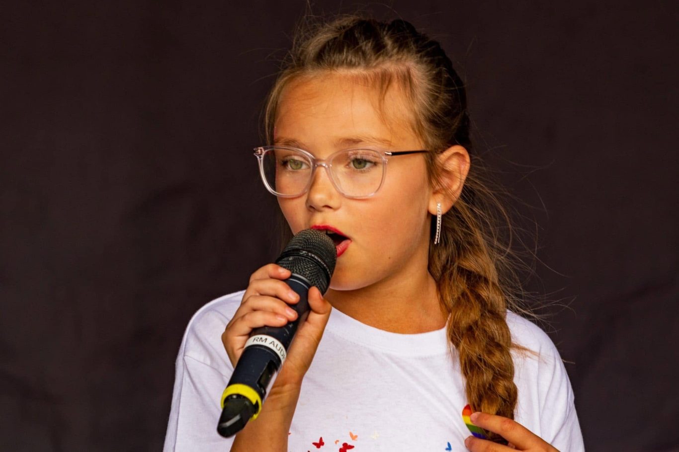 GYG - 2024 Girl with glasses singing into a microphone on stage.