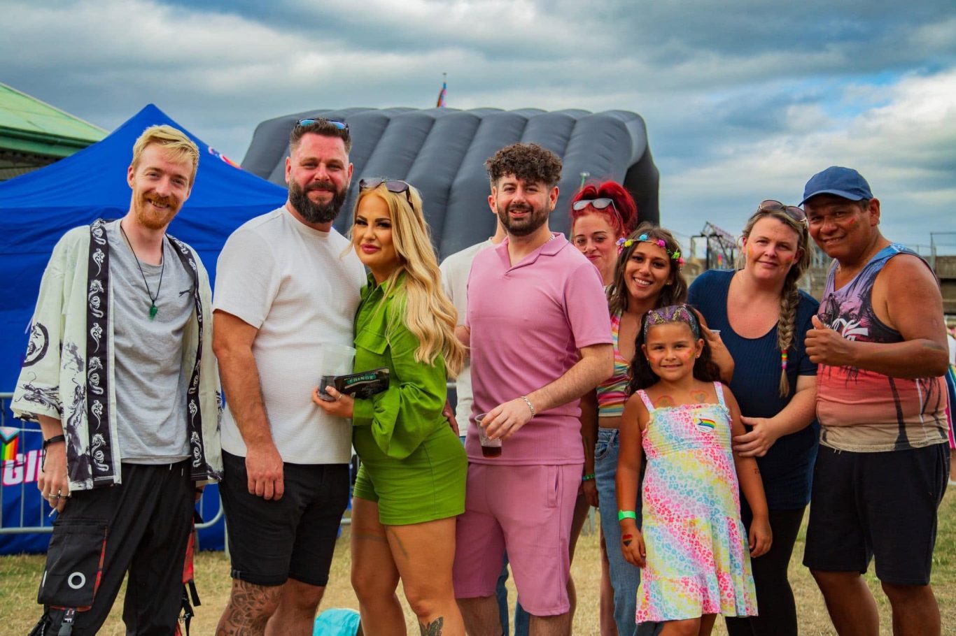 A diverse group of people smiling together at an outdoor event.
