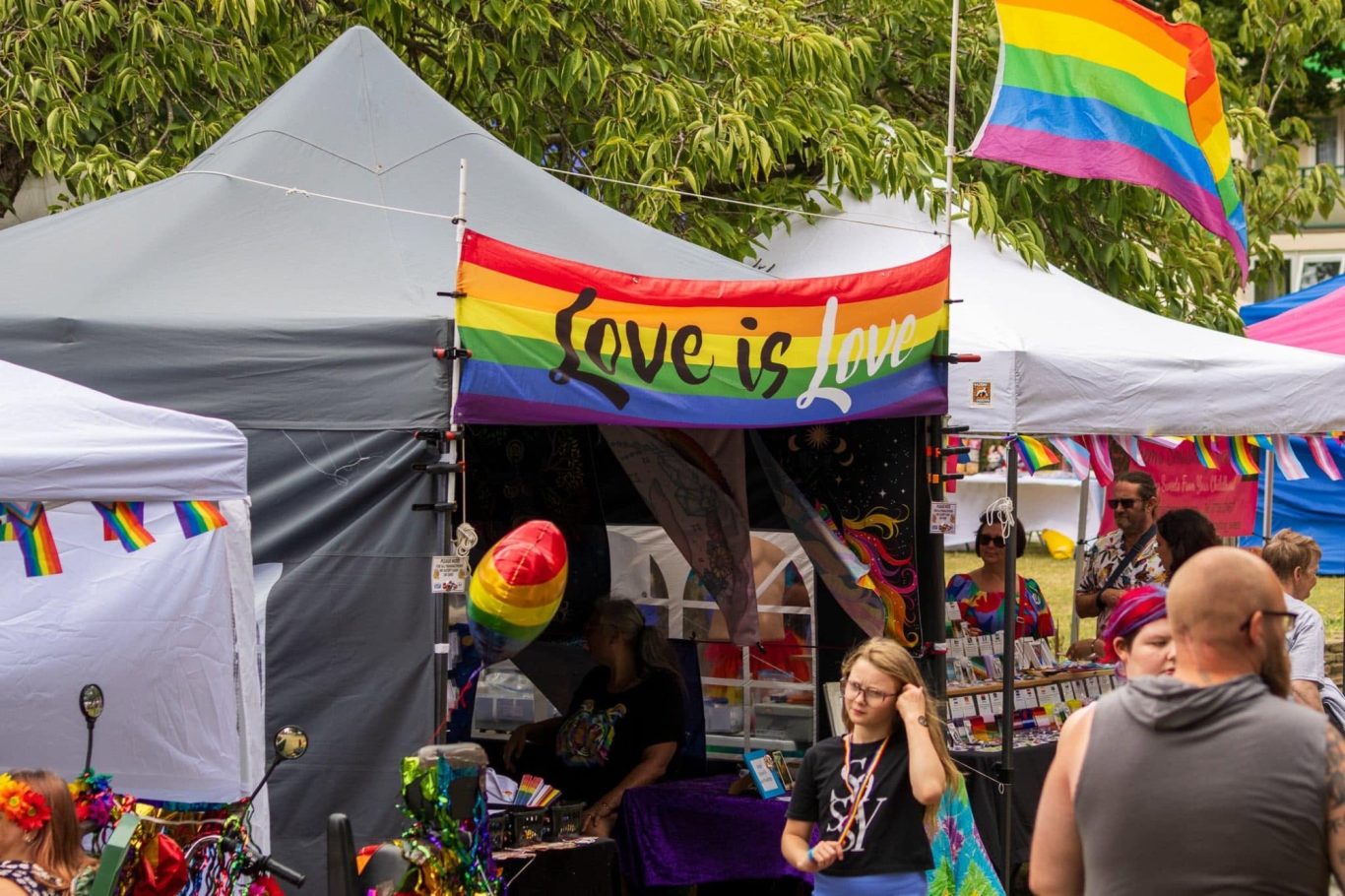 Stalls at a market with rainbow flags promoting love and inclusivity.