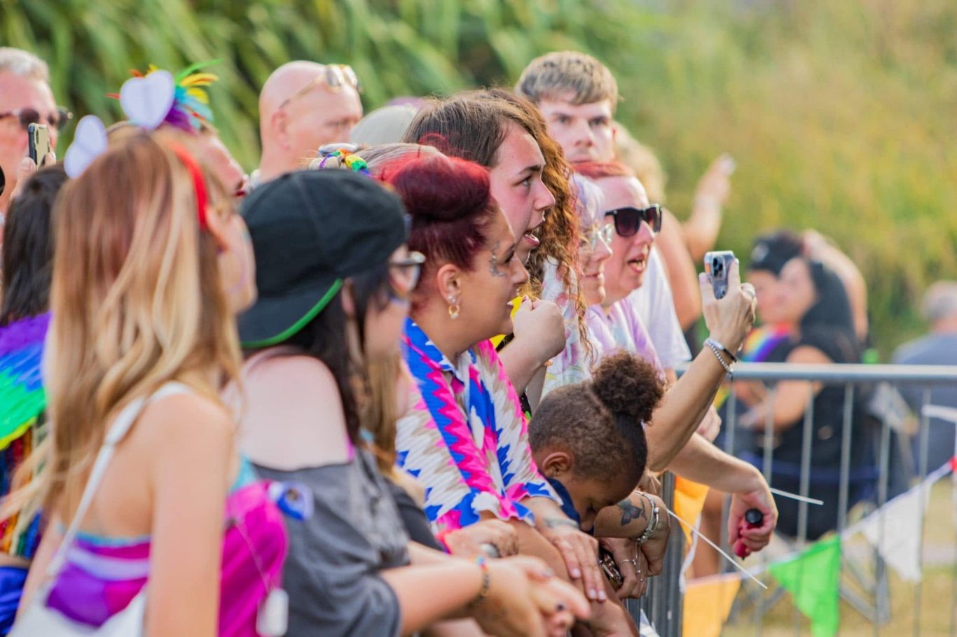 A diverse crowd celebrating at an outdoor event, dressed in colourful attire.