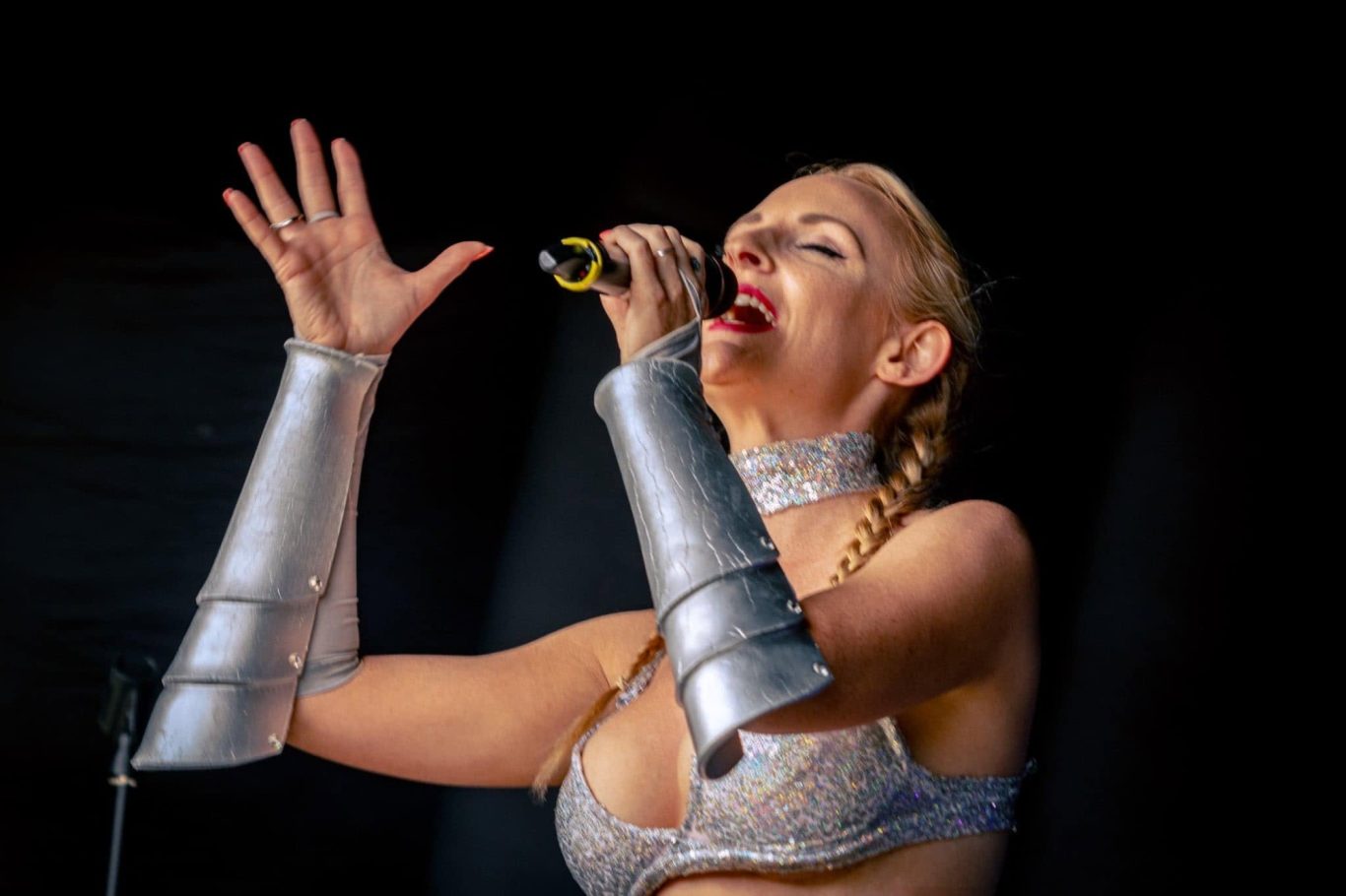 Kylie On Show - 2024 A singer with silver arm accessories performing passionately on stage.