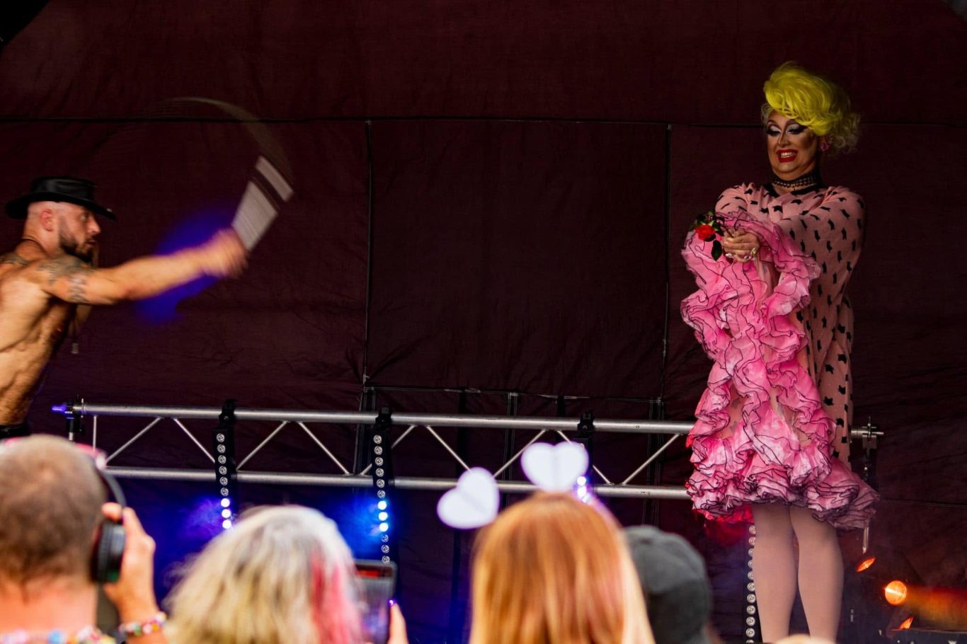 Marshall Arkley - 2024 A drag performer in a pink outfit on stage with a man dancing and a cheering crowd.