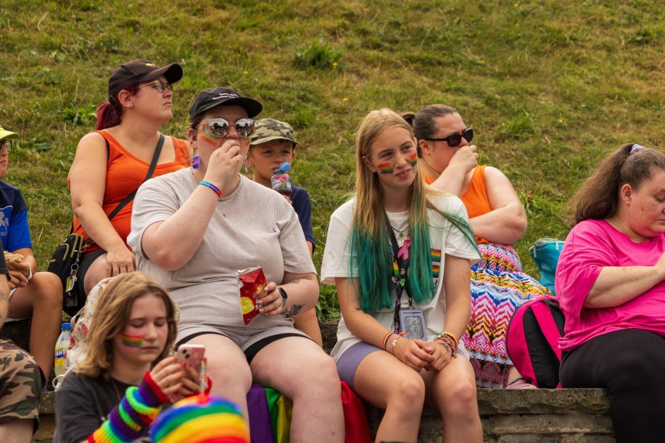A diverse group of people sitting outdoors, enjoying a festival atmosphere.