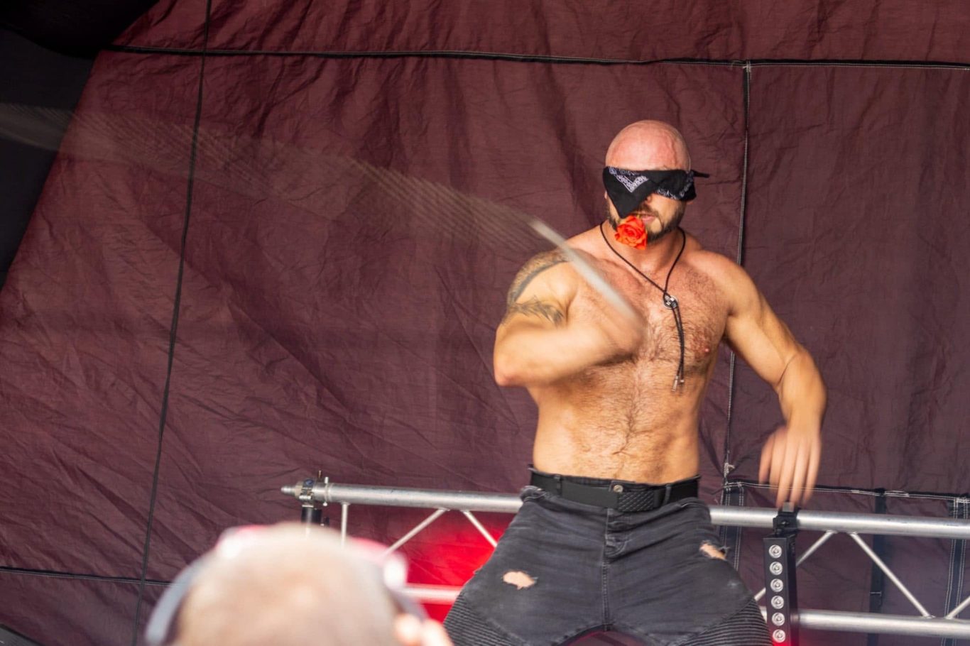 Marshall Arkley - 2024 Muscular performer with a blindfold, demonstrating sword skills on stage.