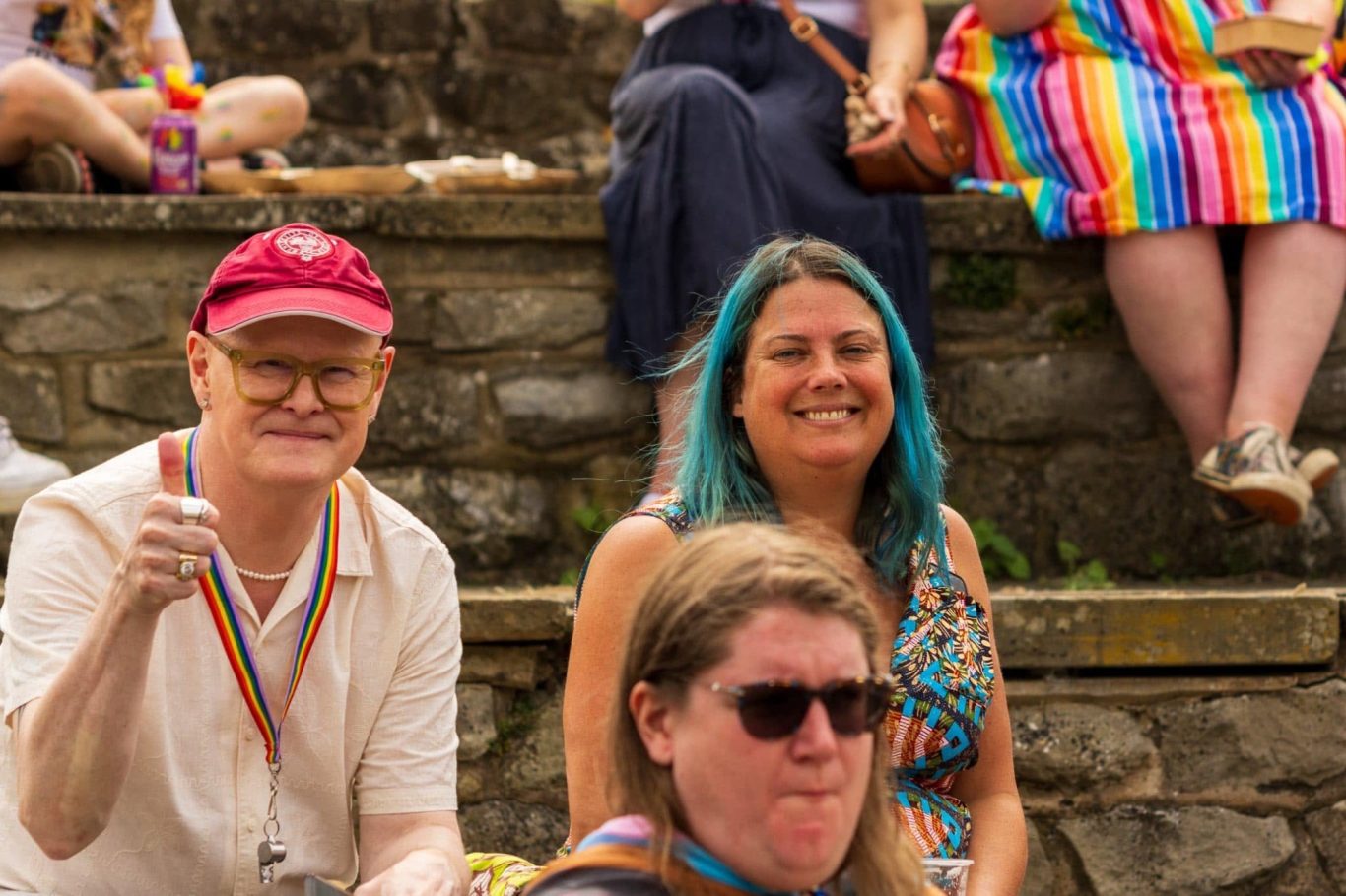 A diverse group of people seated outdoors, smiling and enjoying a celebration.
